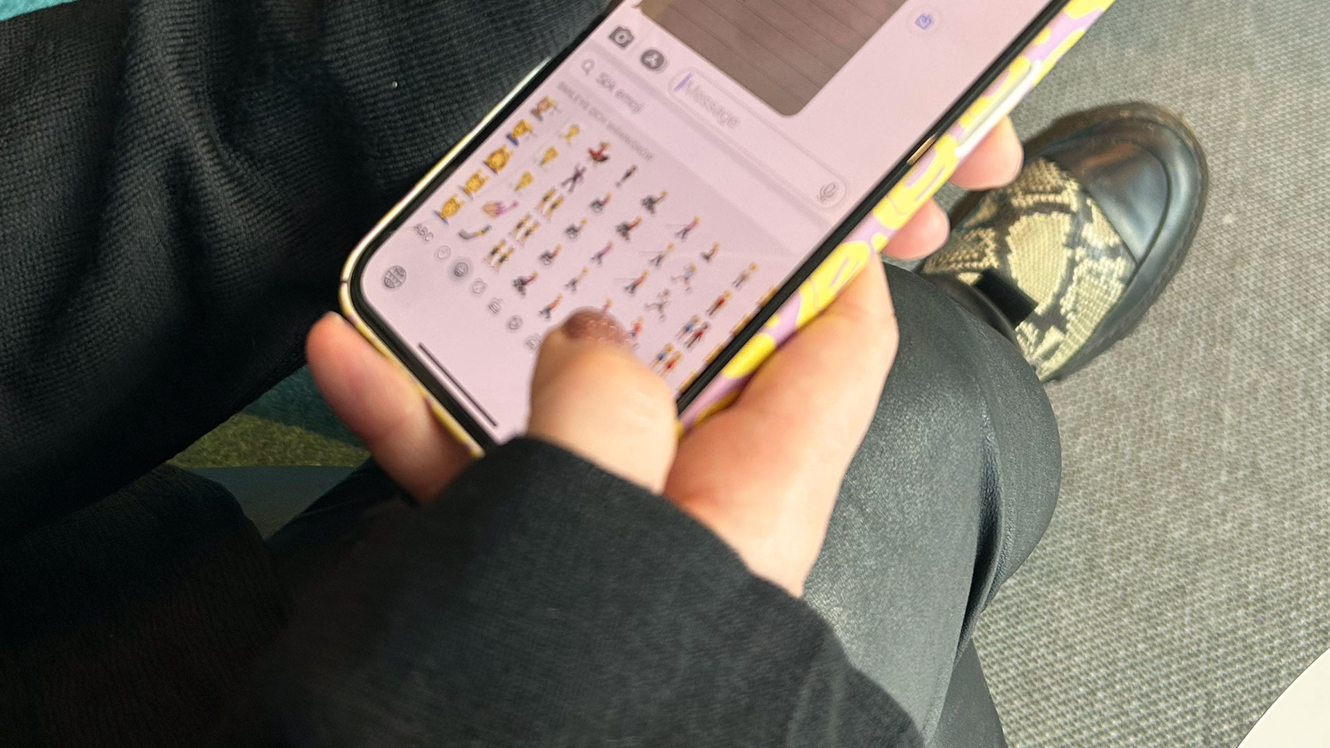 Hand som håller i en smartphone, på skärmen syns emojis.