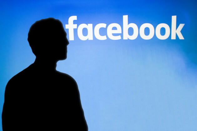 Mark Zuckerberg i profil framför en bild av Facebook